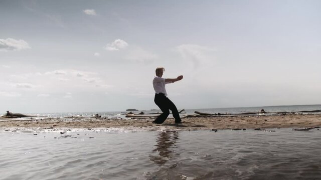blonde girl sensually dancing on a background of the sea in white and black clothes