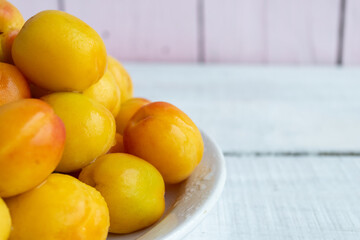 Fresh apricots on a plate on a wooden background. Summer harvest
