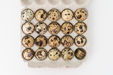 Quail eggs in the egg tray. In one Department, instead of an egg, there are coins. Concept of earnings and expenses in agriculture.
