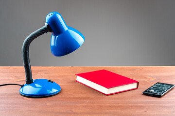 a table lamp and a book next to them a broken smartphone on the table