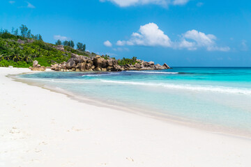 Ocean waves, pristine blue color lagoon and granite rocks on Anse Coco beach, La Digue Island, Seychelles