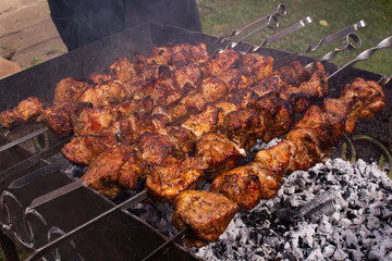 shish kebab in the open air on the grill.cooking meat on the street. street food. picnic. family rest. meat on the shampoo. heat from roast meat. heat from coals on the grill. Shish kebab from chicken