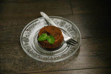 Chocolate brownie on a serving plate decorated with mint leaf on top.