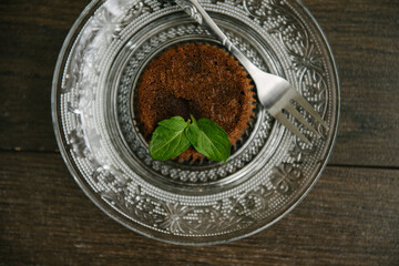 Chocolate brownie on a serving plate decorated with mint leaf on top.