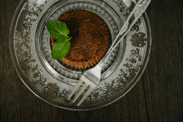 Chocolate brownie on a serving plate decorated with mint leaf on top.