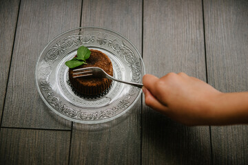 Chocolate brownie on a serving plate decorated with mint leaf on top.