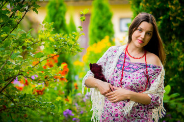 pregnant girl in a summer dress walks in the garden with wildflowers,
toy bear in hands