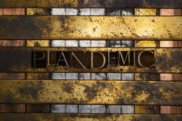 Photo of real authentic typeset letters forming Plandemic text on vintage textured silver grunge copper and gold background