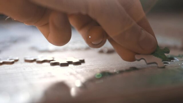 Male hand puzzling, adding pieces to a puzzle- slow motion, tracking shot