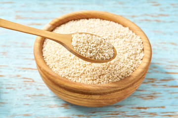 white sesame seeds in a wooden bowl  on a rustic table, close-up.