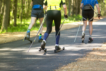 A man rides a ski roller on an asphalt road in the Park in the summer.