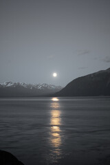 Full moon above the snow capped mountains of Alaska