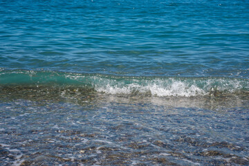 Small sea wave reaching a calm beach. Front view close-up.