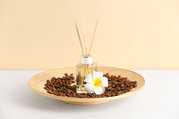 Plate with reed diffuser, coffee beans and flower on table