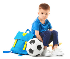 Cute little boy with schoolbag and ball on white background