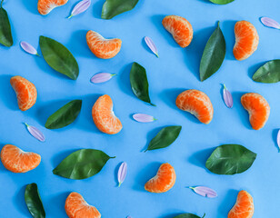 fruit and flower ornament.

Tangerine slices,  and leaves laid out with an ornament on a blue background, close-up
