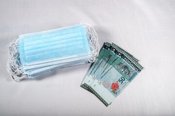 Face masks, the new world currency in Malaysia. Corona Cov19 crisis makes face mask to the most wanted equipment. Prices rising up. Mouth mask with Malaysia Ringgit money on a white background.