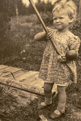 Latvia - CIRCA 1930s: Portrait of girl at hand pump well in garden. Vintage archive Art Deco era photography