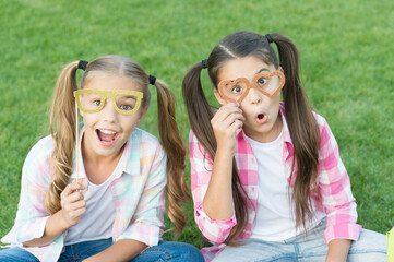 Looking fancy. Party girls wear prop glasses on green grass. Playful friends. Happy childhood. Fashion and beauty. Carnival fashion accessories. Summer fashion. Fashion style. Accessorize your look