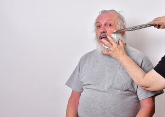 Scared man is getting a shave from a woman using a huge hunting knife..Self isolated man getting  a primitive shave with a large knife.