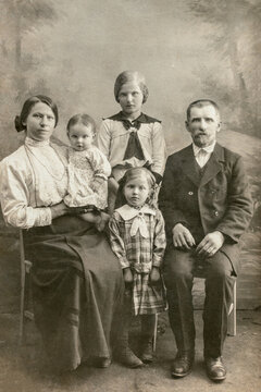 Germany - CIRCA 1910s: A family studio shot of mature male with young woman and three children in studio. Vintage Carte de Viste Edwardian era photo
