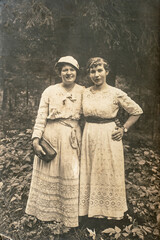 Fototapeta na wymiar Latvia - CIRCA 1920s: Full body shot of two young women in forest. Vintage Carte de Viste Edwardian era photo