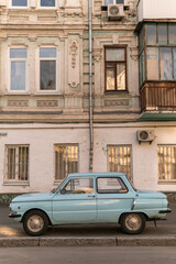 Fototapeta na wymiar Kyiv (Kiev), Ukraine - June 07, 2020: An old blue car (ZAZ Zaporozhets) which was very popular in 1980s in front of a prerevolutionary building 