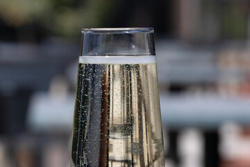 Naklejka premium Close up on a flute of prosecco with bubbles rising to the surface over a blurred background with copy space