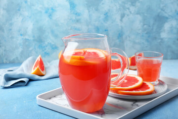 Glass and jug of fresh grapefruit juice on table