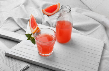 Glass and bottle of fresh grapefruit juice on table