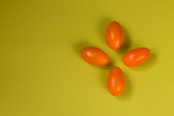 Orange tomato on olive color background. Horizontal position. Flat lay. Copy space.