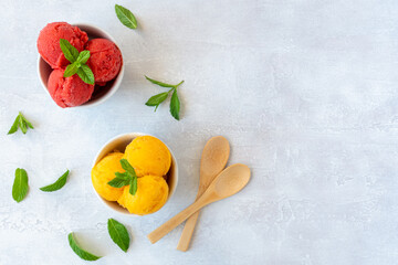 Ice cream scoops in bowls with strawberry and mango flavors. Top view