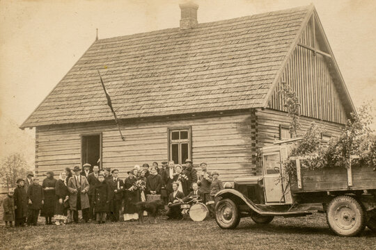 RUSSIA - CIRCA 1920s: Vintage photo shows newlyweds bridesmaids bridesmen and other wedding guests at house. Old truck. Archive black and white photography