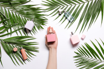 Female hand, perfumes and tropical leaves on white background