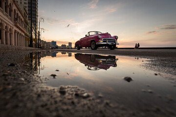 Fototapeta na wymiar Old car on Malecon street of Havana with colourful sunset in background. Cuba