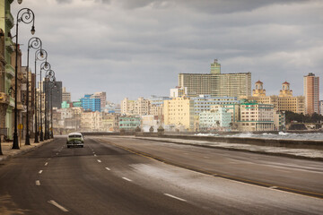 Old car on Malecon street of Havana with storm clouds in background. Cuba