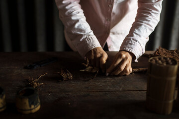 Hands of a woman rolling a cuban cigar in a beautfiul ambient. Vinales, Cuba