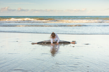 Child exercises and meditates on the beach sand