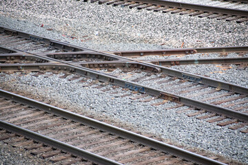 Train tracks intersecting on gravel for trains for transportation, shipping, cargo, and other aspects of the train industry and transit traffic and infrastructure.