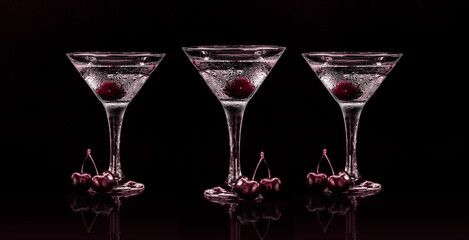 Set of glasses of sweet martini dry cocktail with cherries in black background