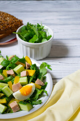 Fresh salad with arugula, codfish liver, cucumbers and sweet pepper, close up