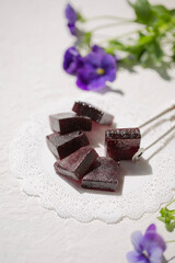 On a white table, marmalade is dark red in color from grapes.
