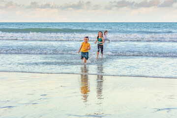 Children running in the water on the beach on a beautiful day