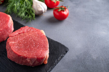 Raw meat steak on black stone board. Copy space