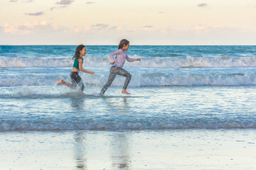 Children running on the beach juggling joy