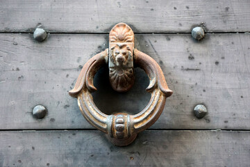 Rusty vintage door knocker with a lion head in Bergamo, Italy.