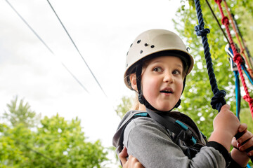 Fototapeta na wymiar Little girl enjoying climbing on rope in adventure park 