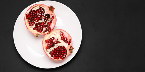Ripe pomegranate on a black background with a copy of space. Cut the red fruit of pomegranate. Top view, copy space.