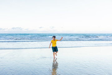 Fototapeta na wymiar Child dancing cheerfully on the beach with shadows