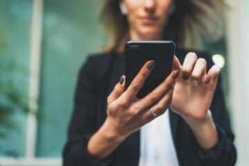 Closeup of female hands using modern smartphone device outdoors, focus on cellphone, social network and communication concept.